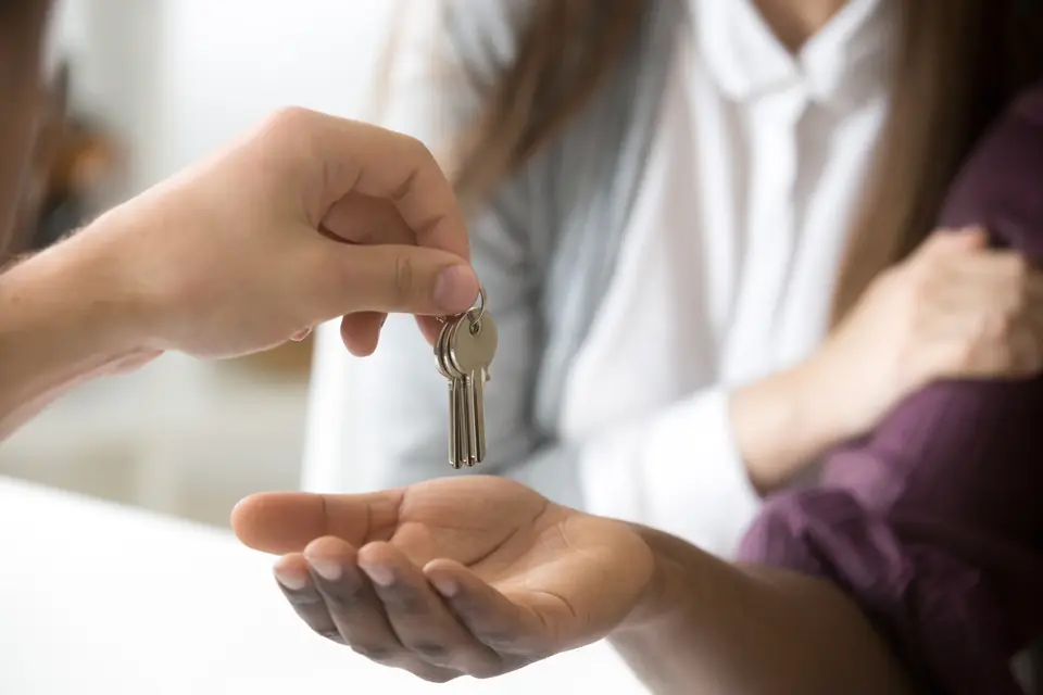 Chave de casa sendo entregue na palma da mão.